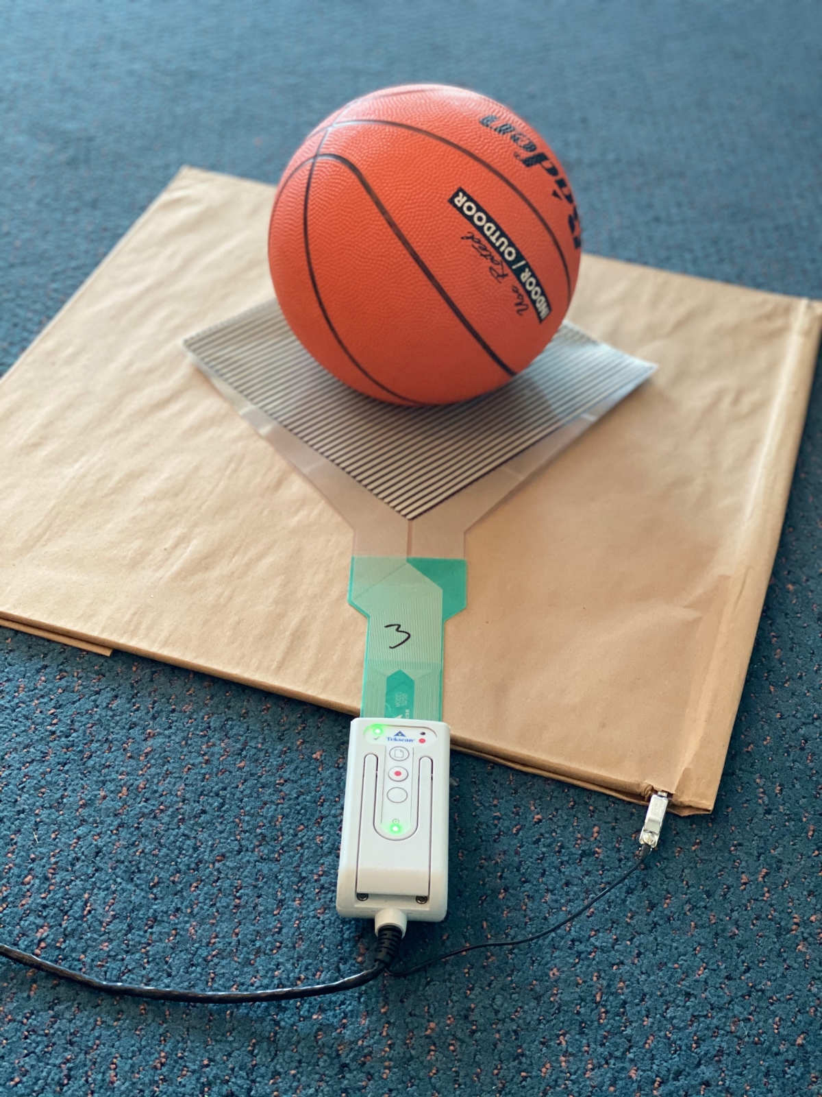 Figure 1: Image of the water-filled basketball, scanning electronics, and 5250 pressure mapping sensor used in the drop-test experiment.